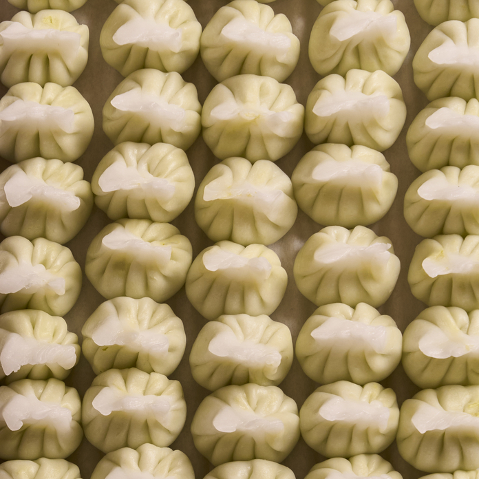 Rows of steamed dumplings with white filling in a grid pattern on a tray.